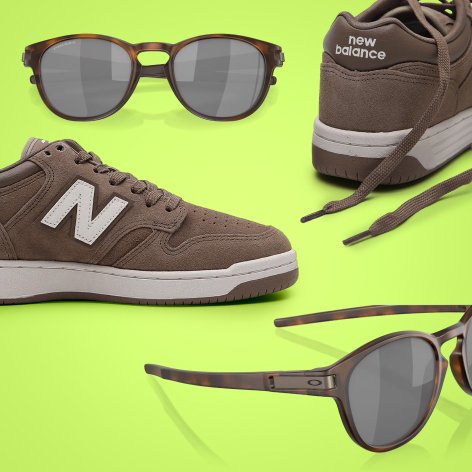 Imagem de um tênis New Balance e óculos Oakley sobre fundo verde, destacando a combinação de estilo e conforto.