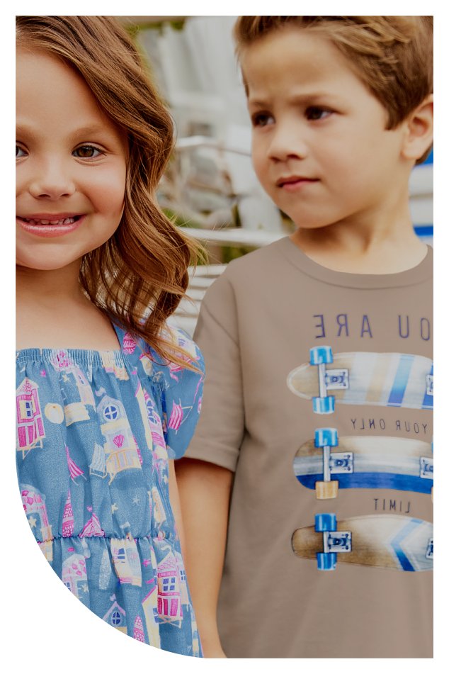 Duas crianças lado a lado, vestindo camisetas, sorrindo e posando para a foto em um ambiente ao ar livre.