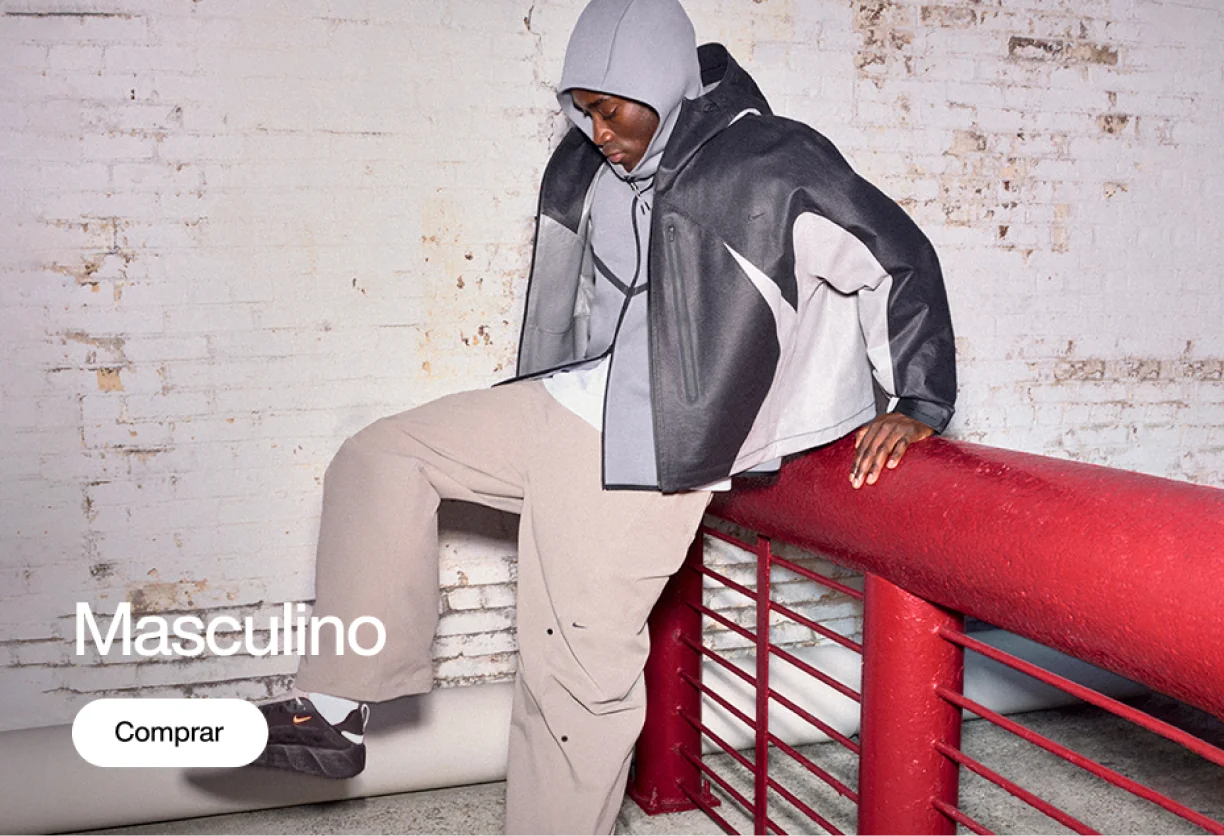 Modelo usando jaqueta Nike preta e cinza com capuz, calça bege e tênis escuros, sentado sobre um corrimão vermelho em ambiente com parede de tijolos brancos. Texto: “Masculino” e botão “Comprar”.