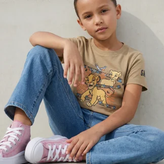 Criança usando camiseta estampada, jeans e tênis rosa